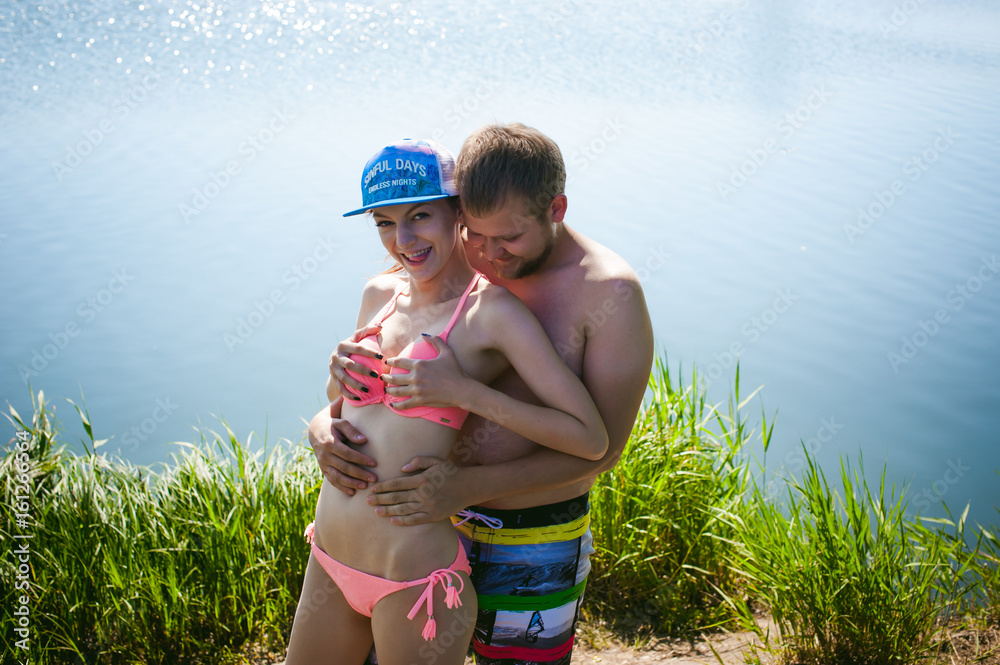 Young couple, man with beard and attractive girl in swimsuit, hugging  against pond background, enjoying a warm summer day Stock Photo | Adobe  Stock