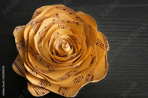 Beautiful rose made of music notes on wooden table closeup photo