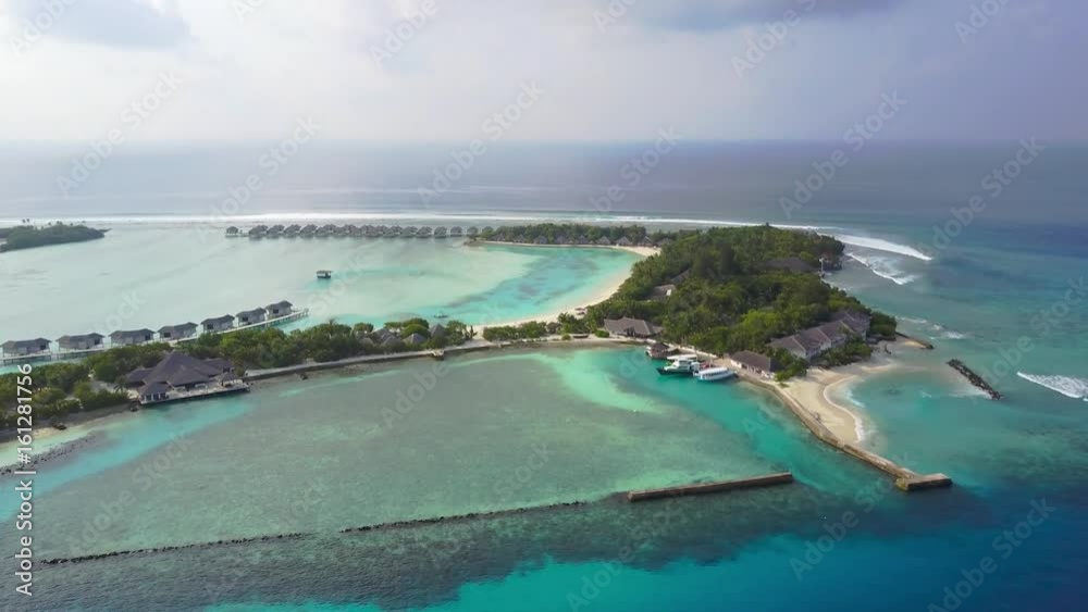 Aerial view of tropical island resort hotel with white sand palm trees and turquoise Indian ocean on Maldives, drone footage from above Aerial view of tropical island resort hotel with white sand palm trees and turquoise Indian ocean on Maldives, drone footage from above