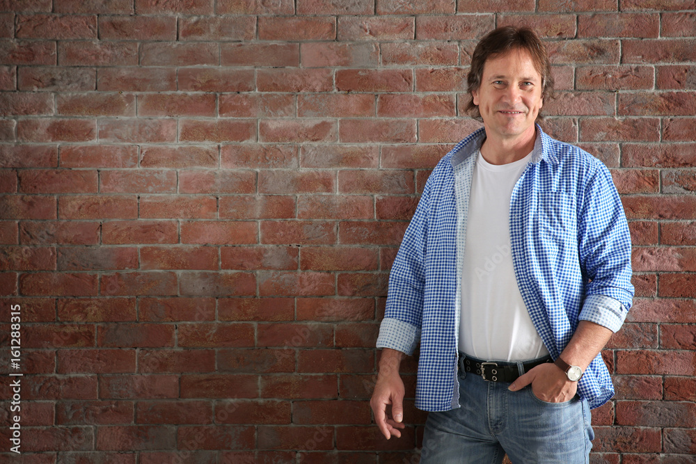 Mature man posing on brick wall background Mature man posing on brick wall background