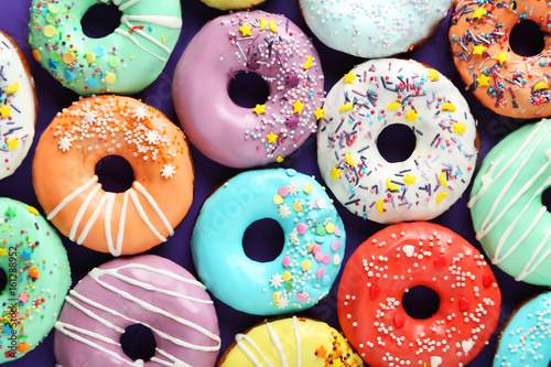 Fotografia Tasty donuts with sprinkles on paper background