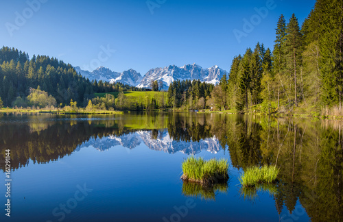 Idyllic alpine scenery, snowy mountains mirroring in a small lake, Kitzbühel, Tyrol, Austria