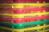 Close-up, full frame view stack of colorful plastic baskets with steel handle. Heap of rainbow color (yellow, red, green, blue) shopping baskets in a farmer market at Texas, US. Vintage tone.