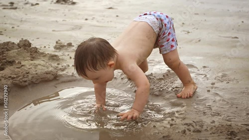 Cute Baby Boy Playing in Wet Sand at the Beach. 4k footage photo