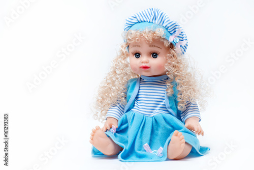 Blond baby doll in blue and white striped dress and hat on white background