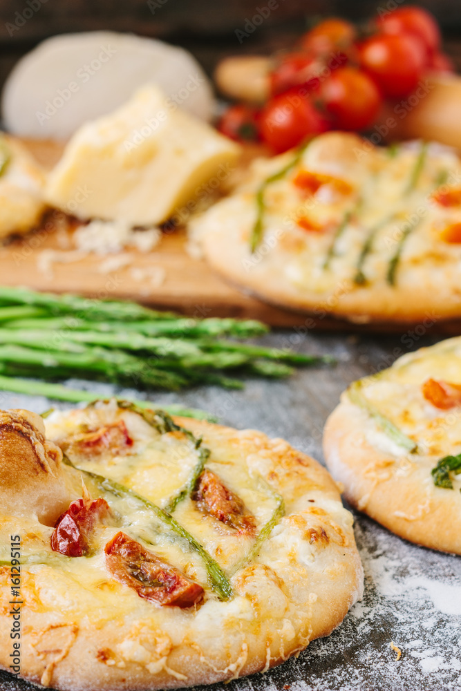 Mini pizza with asparagus. Traditional small pizza for personal eating filling with cheese, tomatoes and asparagus. Mini pizza with asparagus. Traditional small pizza for personal eating filling with cheese, tomatoes and asparagus.