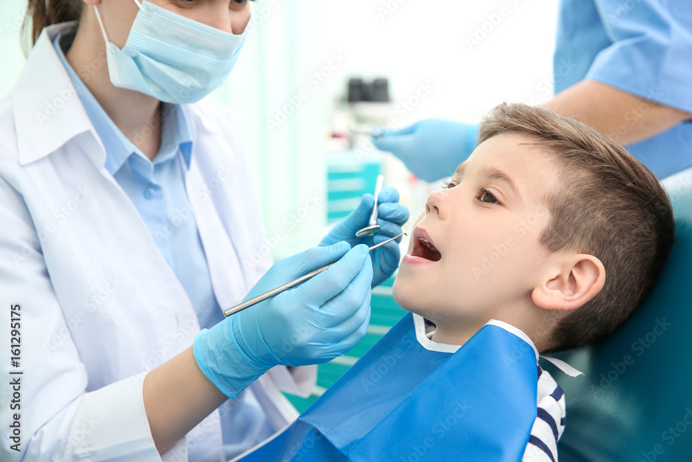 Dentist examining little boy's teeth in clinic Dentist examining little boy's teeth in clinic