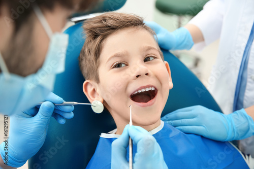 Dentist examining little boy s teeth in clinic