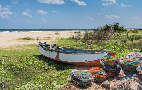 The big fishing boat on the grass of sandy ocean coast with full baskets with color fishing nets and buoyes for them.