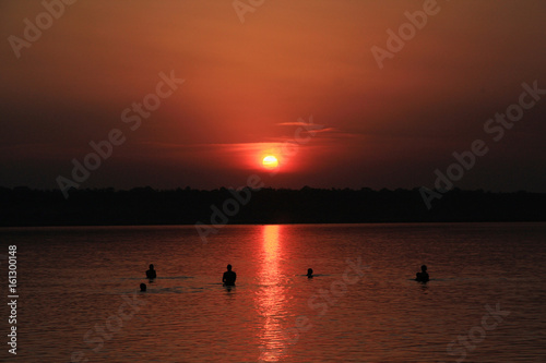 Silhouettes of people bathing in the lake at sunset. Odessa Suvorovo liman Katlabuh, Ukraine. © apeskoff