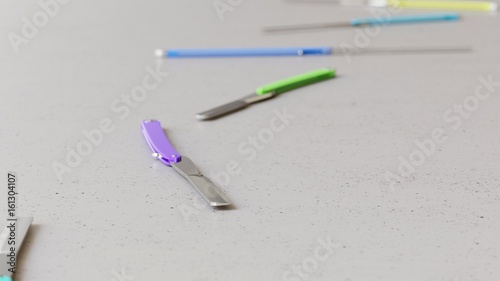 Long isolated line of brightly colored Straight Razors on a neutral surface