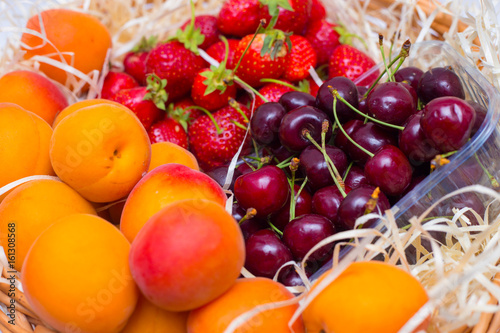 Fruits in a basket of apricots  strawberries and sweet cherries. Summer basket with vitamins  