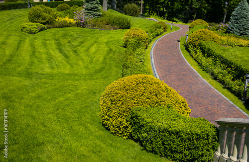 Landscaping in the garden. The path in the garden.Beautiful backyard landscape design,Some flowers and nicely trimmed bushes on the leveled front yard,Landscape formal