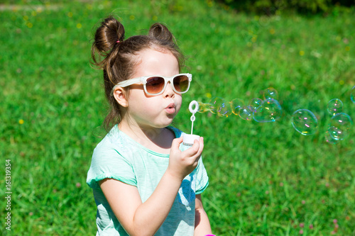 child girl blowing soap bubbles outdoor