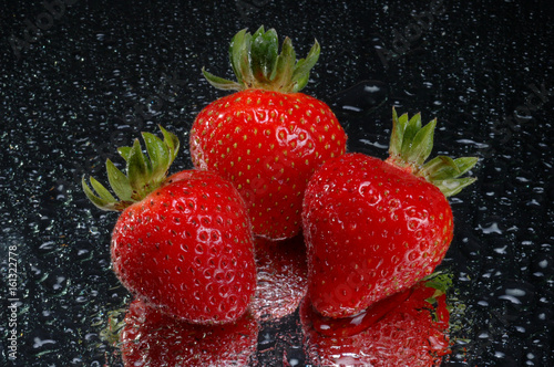 three strawberries on wet glass