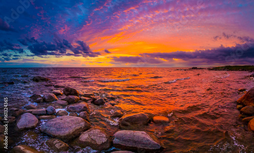 Sunset over the water. Beach with stones.