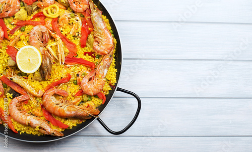 From above paella dish in a pot containing rice and vegetables with seafood. Copy space. photo