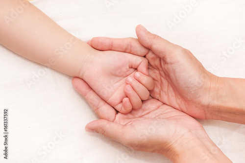 Baby life in mother hand. Mom take care of baby. Hand of baby in hands of parents. 