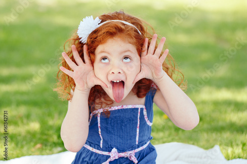 Obraz na plátne Portrait of cute adorable little red-haired Caucasian girl child in blue dress m