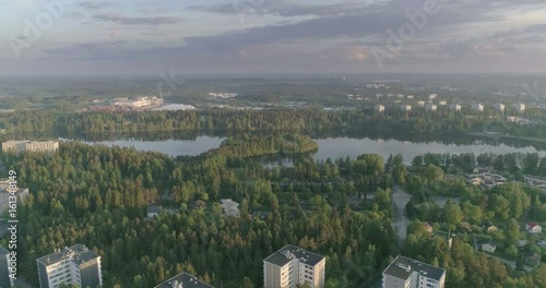 Evening aerial view of lake surrounded by apartment houses and forest in Lahti, Finland, Sideways movement