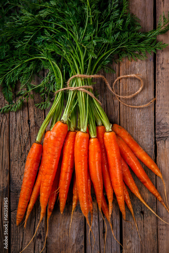 Bunch of fresh carrots with green leaves over wooden background. Vegetable.Food or Healthy diet concept.Vegetarian.Copy space for Text. selective focus.