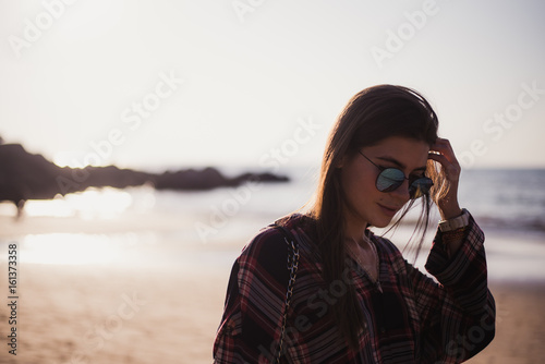 Close up portrait of slim lady in pink t-shirt and sunglasses near big stone at rock beach sea ocean shore. © romankosolapov