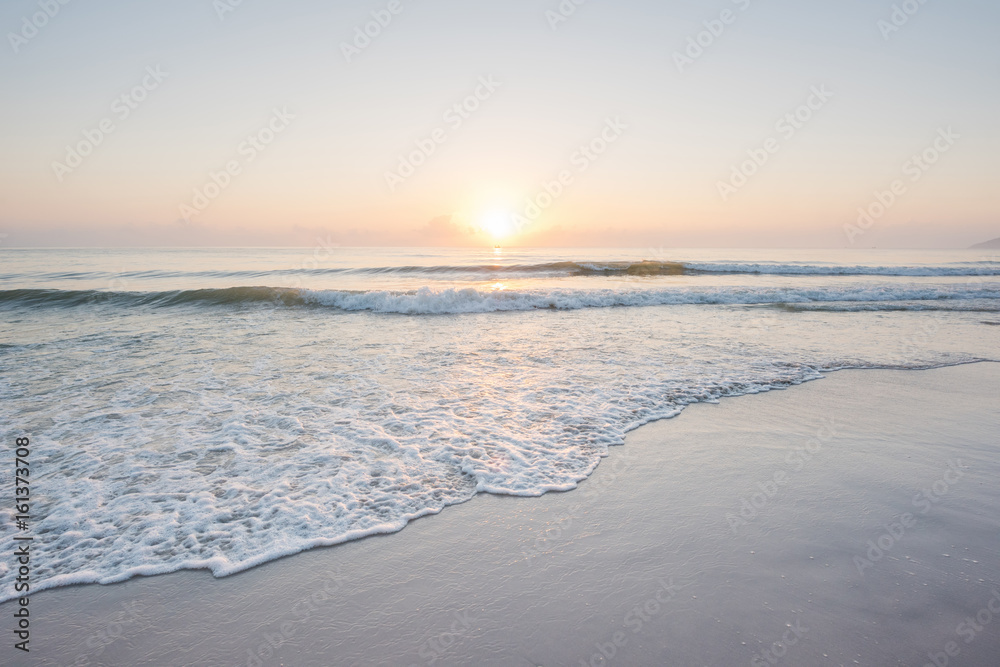 Naklejka premium Piękny zachód słońca i delikatna fala na płytkiej plaży