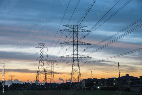 Group silhouette of transmission towers (power tower, electricity pylon, steel lattice tower) at twilight in Humble, Texas, US. Texture high voltage pillar, overhead power line, industrial background. photo