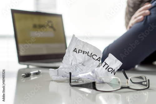 Ripped job application paper. Problem in search. Depressed and unemployed man crying on table. Tired of trying after rejections from employers. Job seeker not satisfied with career. Out of work.