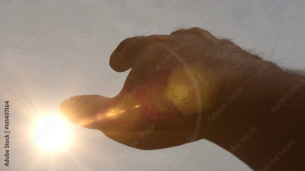 The hand holds up the sky catching the sun. The hand holds up the sky catching the sun.