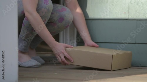 A female picks up a package from outside his front door