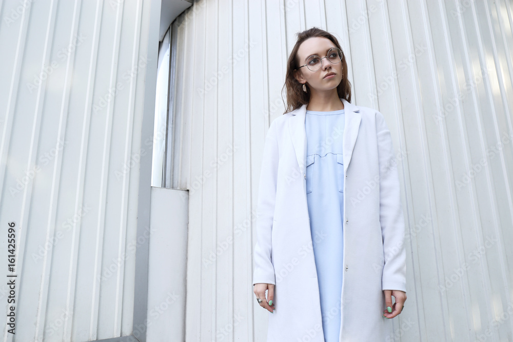 fashion portrait of young elegant woman outdoor in jacket, dress, glasses