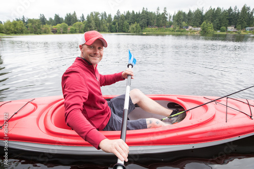 Handsome man in a red kayak on a lake