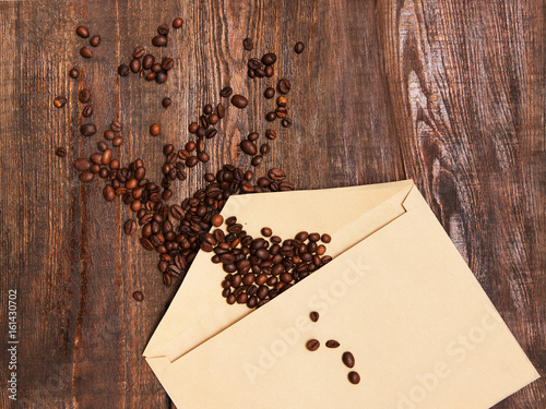 Coffee beans in envelope on wooden background. Charge of energy, help in a difficult situation concept photo