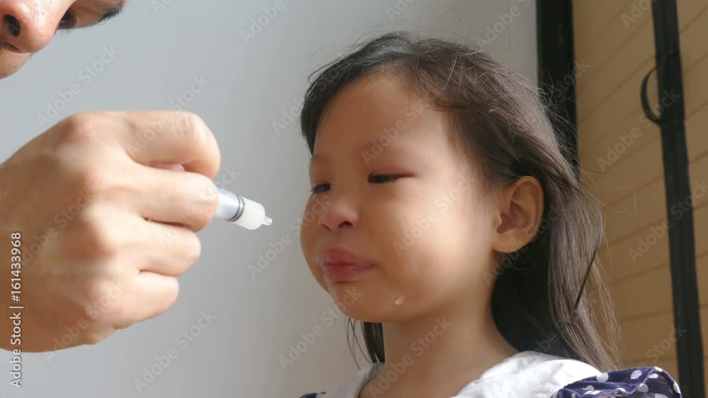 Asian girl crying before her father gives medicine Asian girl crying before her father gives medicine