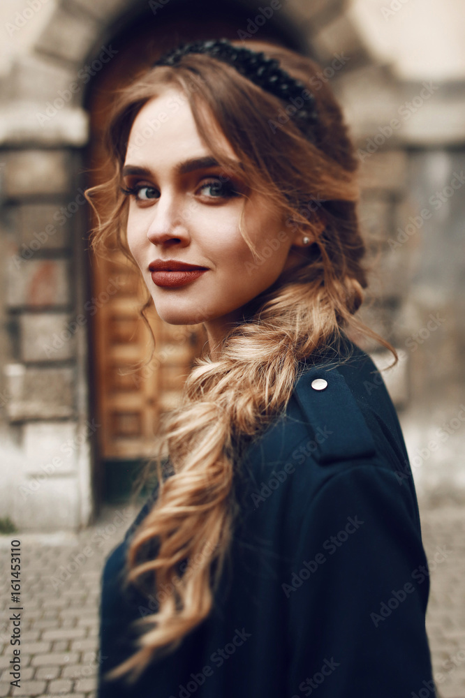 Stunning woman in black coat poses before an old building Stunning woman in black coat poses before an old building