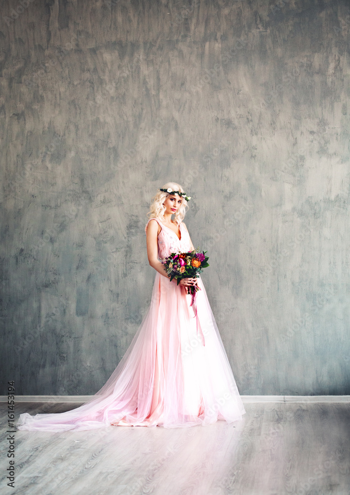 Glamorous Woman in Fashionable Dress Posing. Summer Blonde Beauty. Perfect Fashion Model in Pink Dress on Grey Wallpaper Background Glamorous Woman in Fashionable Dress Posing. Summer Blonde Beauty. Perfect Fashion Model in Pink Dress on Grey Wallpaper Background