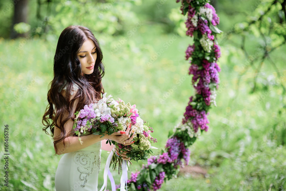 Bride with long dark hair stands before a large circle of lilac Bride with long dark hair stands before a large circle of lilac