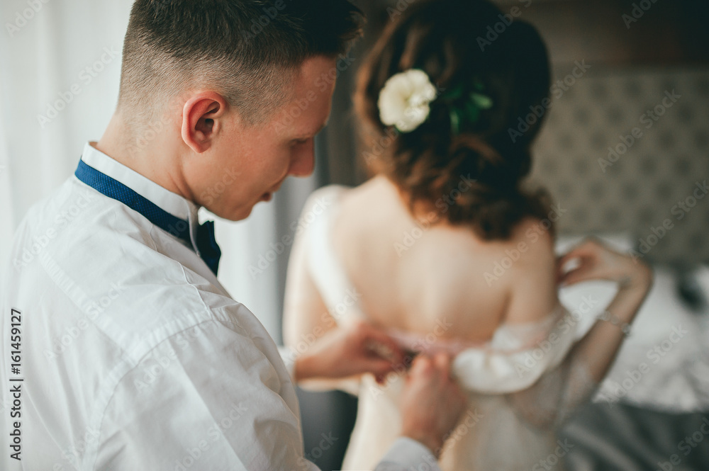 The groom dresses the bride. Wedding preparations The groom dresses the bride. Wedding preparations
