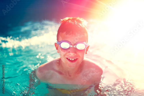 Happy kid in swimming pool enjoying summer holiday in sunset, vintage style