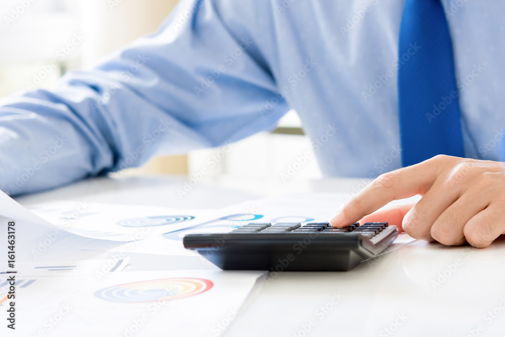 Fototapeta premium Businessman pressing calculator, calculating and analyzing financial data