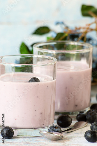  Blueberry dessert. Yogurt in a glass and fresh berries blueberries on a blue wooden table.