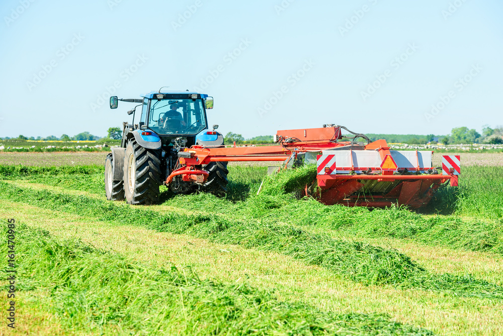 Tractor with hay mower cutting grass for hay on a field. Tractor with hay mower cutting grass for hay on a field.