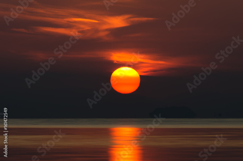 Fototapeta Naklejka Na Ścianę i Meble -  Big sun and orange cloud in sunset sky on the lake.