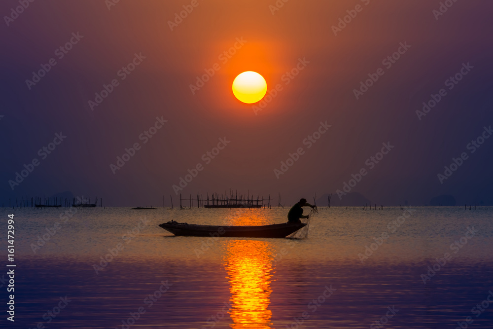 Silhouette fisherman and Sunset sky on the lake in south of Thailand.