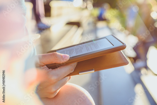 Girl reading e-book in sunny evening, selective focus