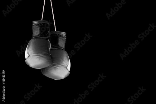 Pair of boxing gloves hanging against a black wall background. Empty copy space for Editor's text. © JuanCi Studio