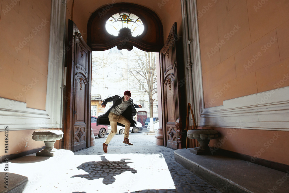 Man in grey coat and beige pants jumps in open doors