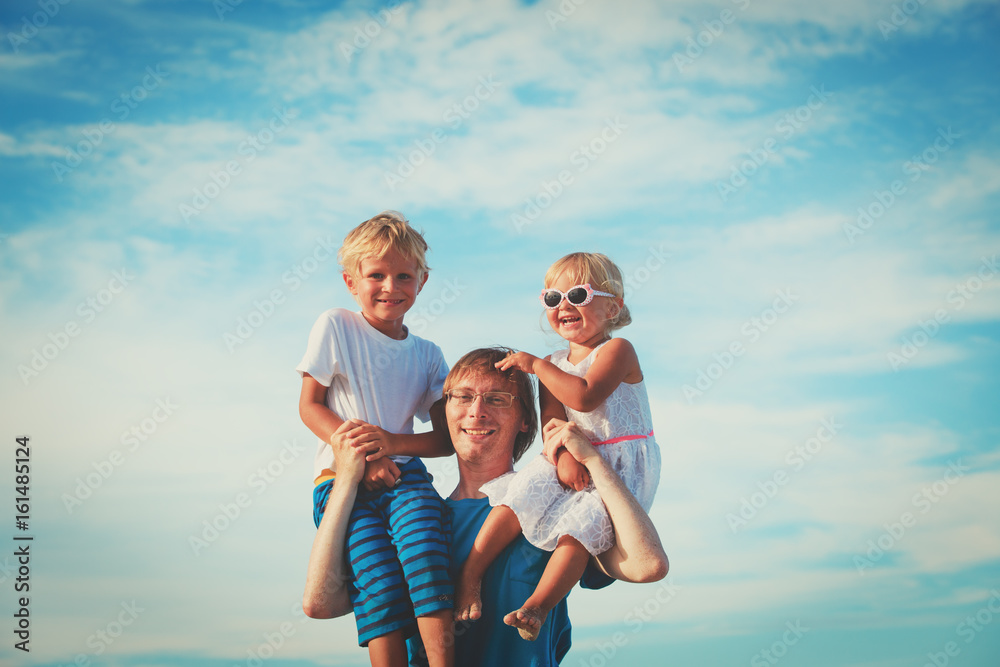 happy father with two kids on shoulders at sky happy father with two kids on shoulders at sky