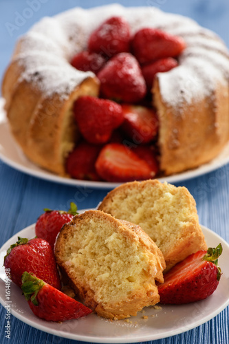 Homemade cake with strawberries on wooden background.